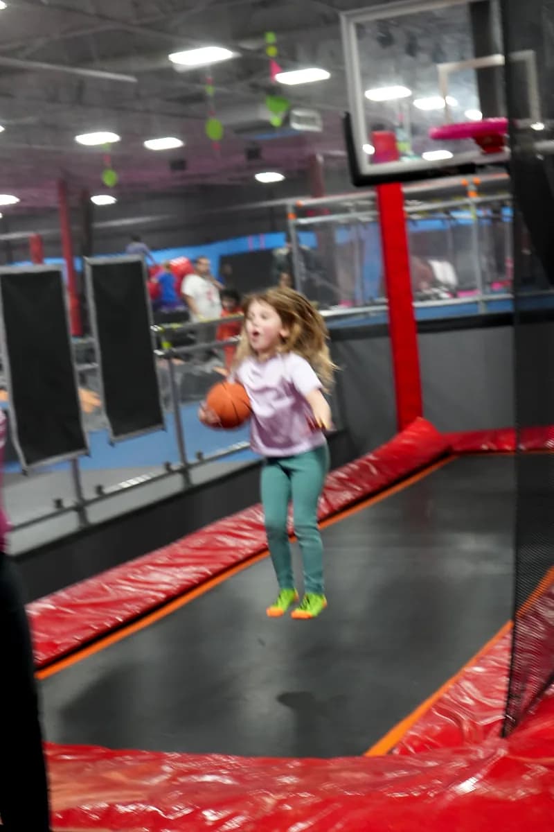 Kid jumping toward the Aero Hoops basketball attraction at AeroSports