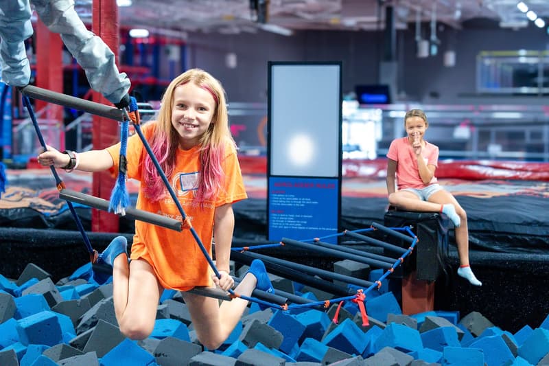 Kids climbing the Aero Ladder obstacle over the foam pit at AeroSports