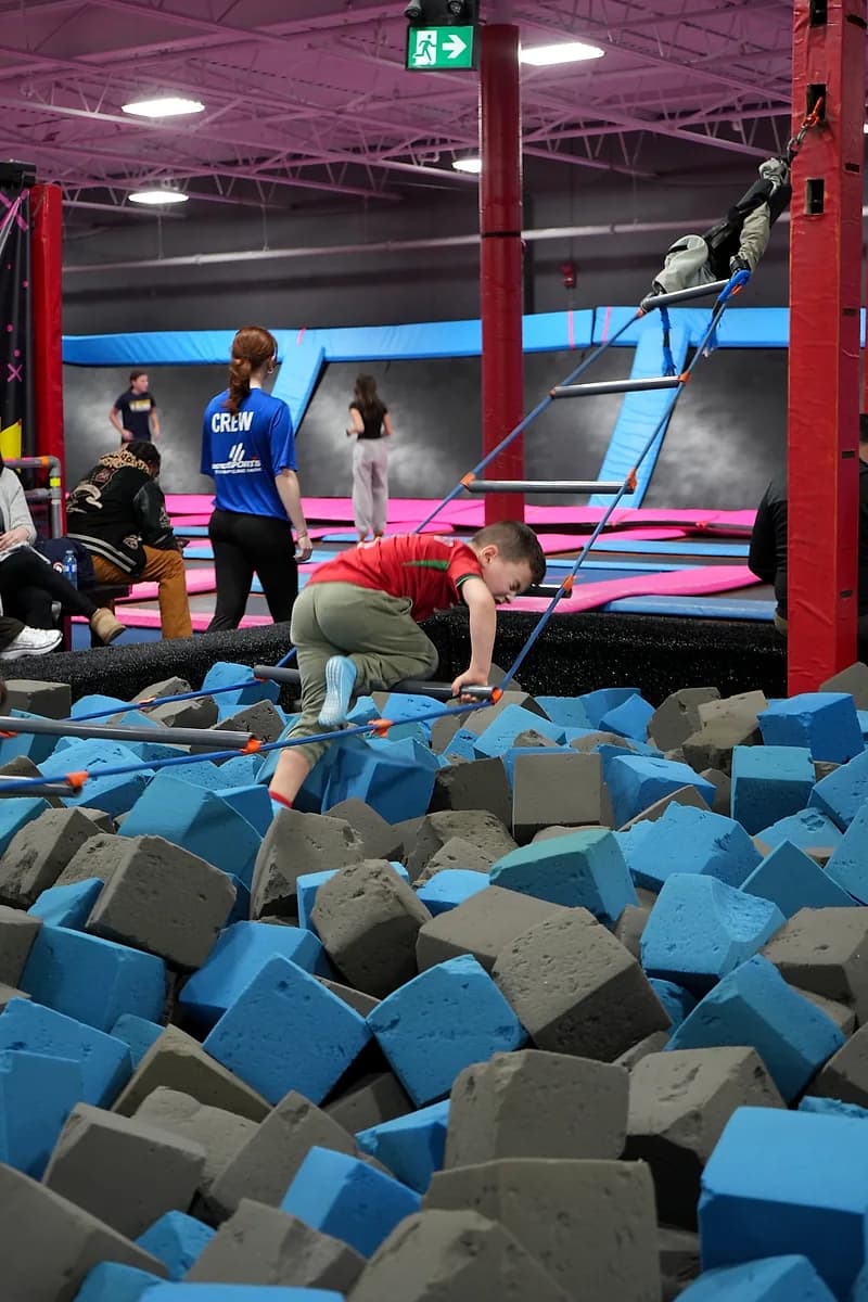 Kids climbing the Aero Ladder obstacle over the foam pit at AeroSports