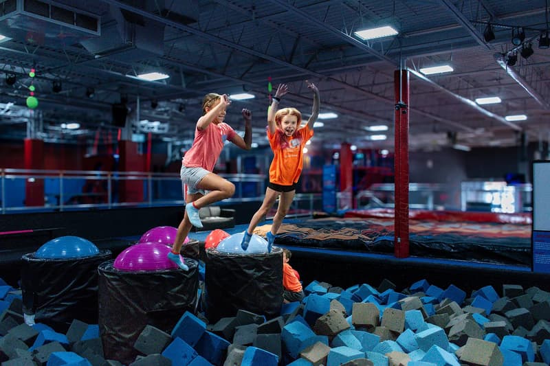 Kids playing on the Battle Beam attraction at AeroSports trampoline park